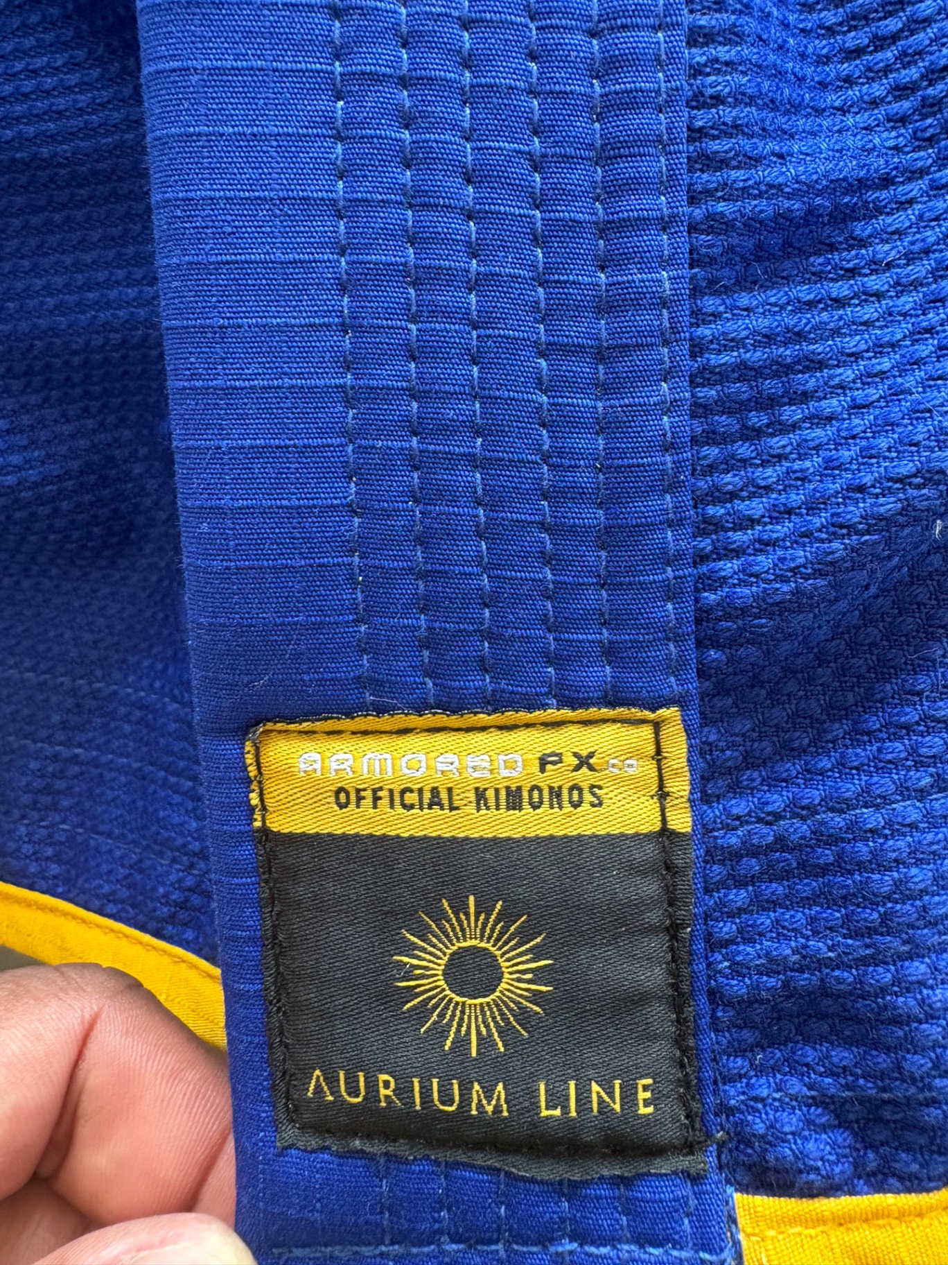 Athletes wearing ARMORED FX gis in white, black, and blue.
